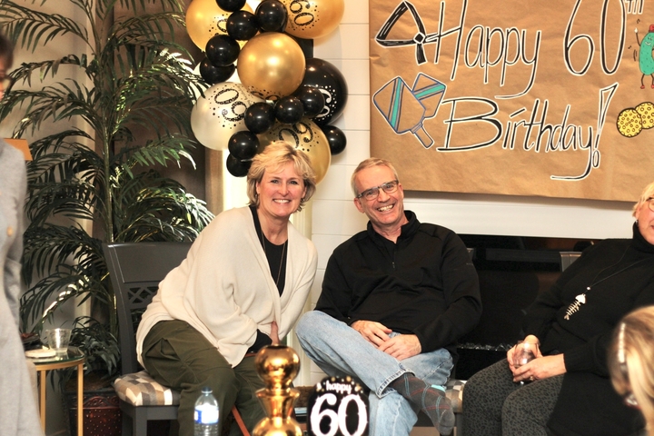 People posing in front of birthday decorations indoors.