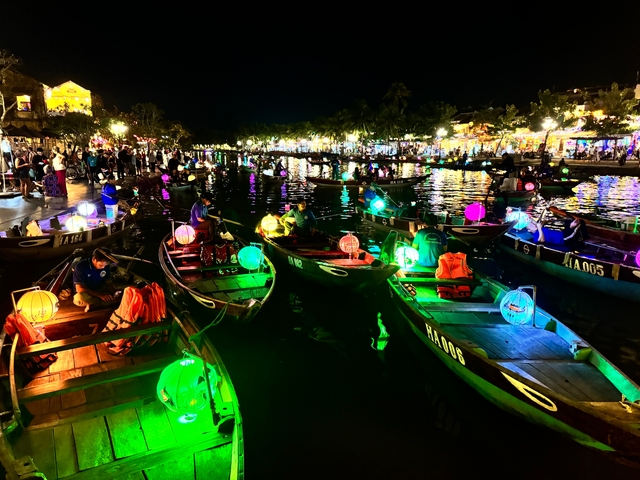 Boats with colorful lanterns on a busy river at night