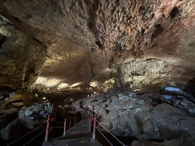 Illuminated cave interior with stalagmites and stalactites.