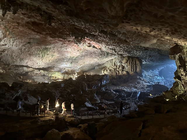 People exploring an illuminated cave interior.