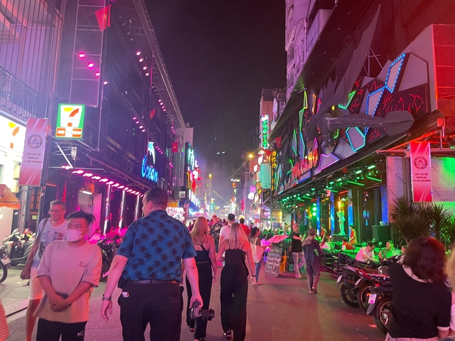 Crowded vibrant street with neon lights at night.