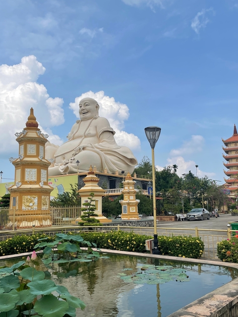 Large Buddha statue and pagoda in a garden setting.