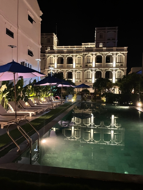 Elegant hotel exterior and pool illuminated at night.