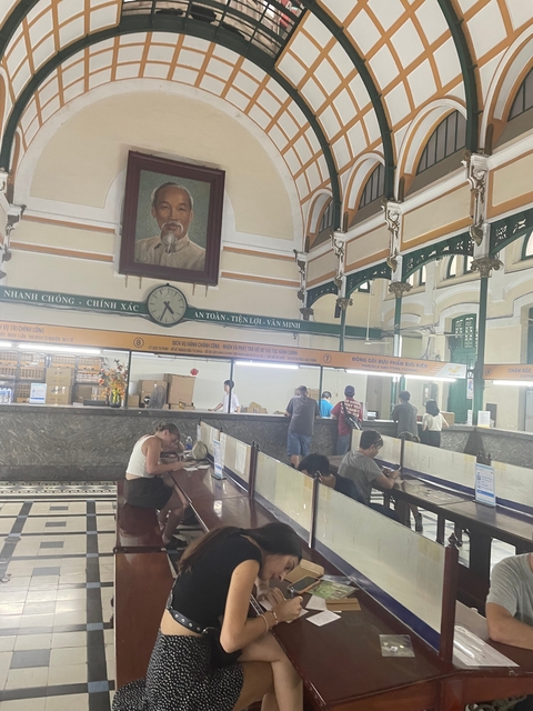 People inside a historic post office with portrait of a famous figure.