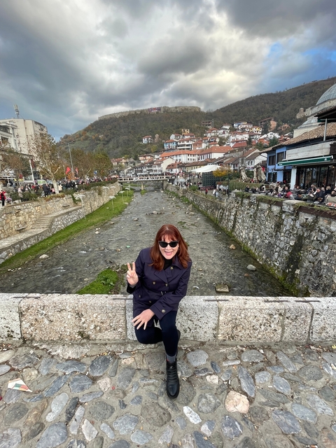 Woman posing on a bridge over a river in an urban area.