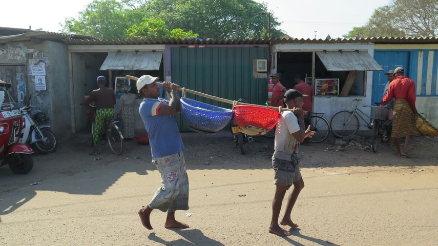 Street market scene with vendors and baskets of goods.