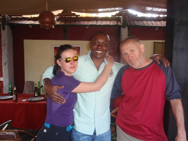 Three people posing for a photo indoors with drinks visible.