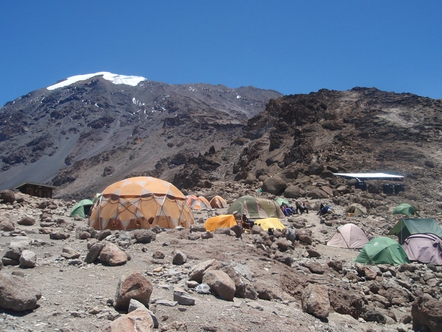 Campsite with tents at the base of a mountain.