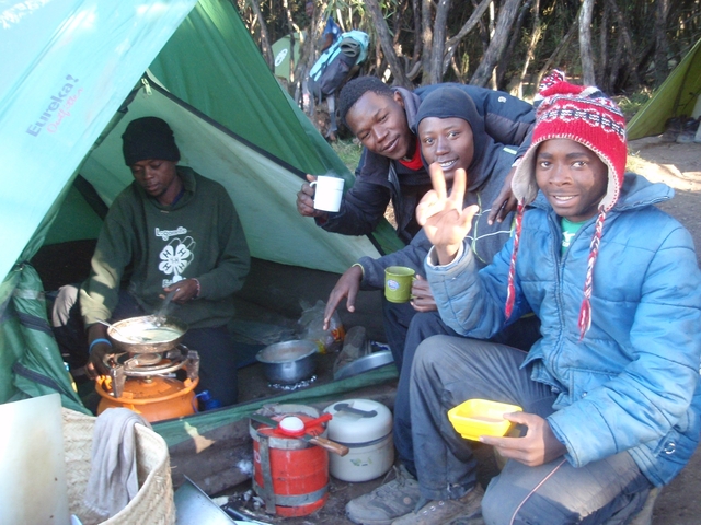 Four people preparing food outside a tent.