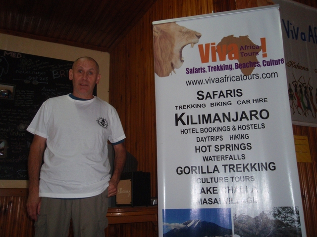 Person standing beside a tourism banner indoors.