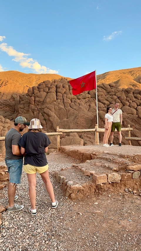 Couple posing in front of a rocky landscape and flag.