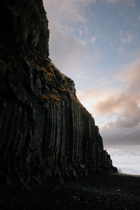 Rocky cliff faces under a sky with clouds and light.