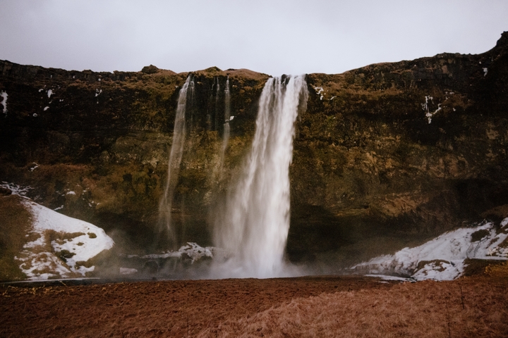 A beautiful waterfall surrounded by snow in Iceland.
