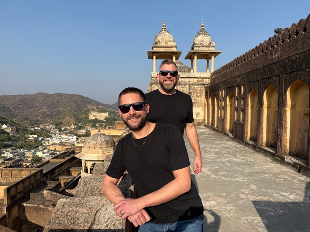 Two men posing on a terrace overlooking a city.
