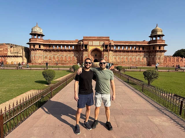 Two men posing in front of a large fort.