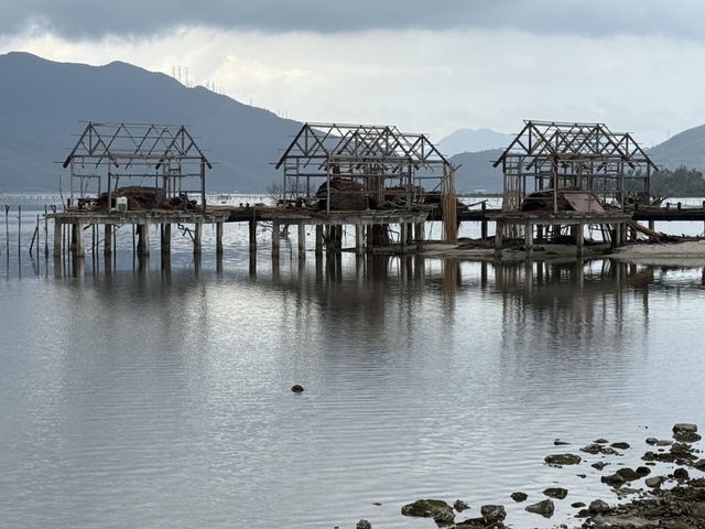 Wooden structures on stilts over water, frame under construction.