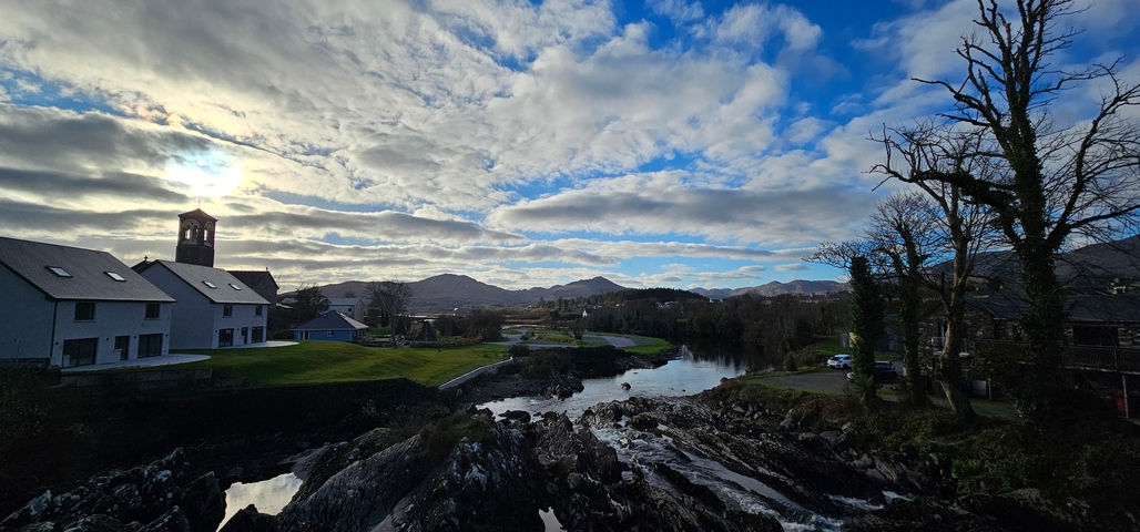 Scenic river landscape with houses and mountains.