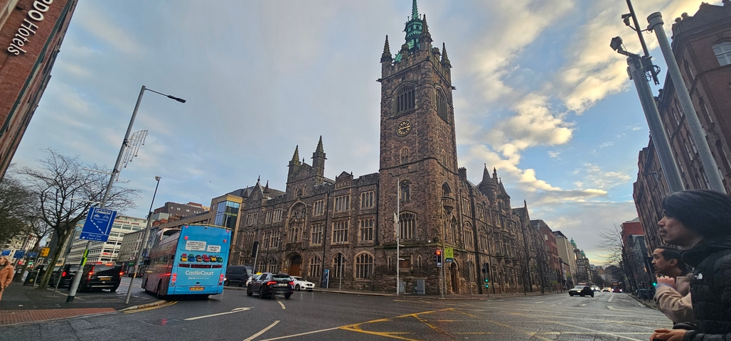 Historic building with high tower and clock on a city street.