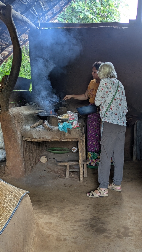 Two people cooking on an outdoor clay stove.