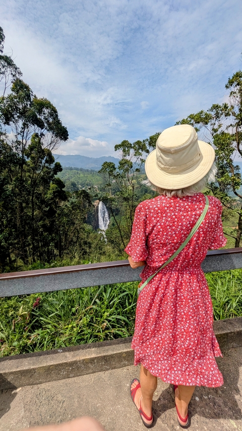 Person in a hat looking at a waterfall through a viewpoint.