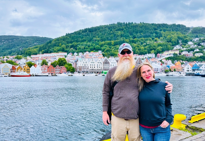 Couple posing by a waterfront with colorful buildings in the background.