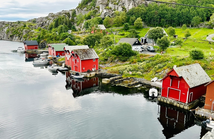 Scenic view of red cottages by the water reflecting in the still water.
