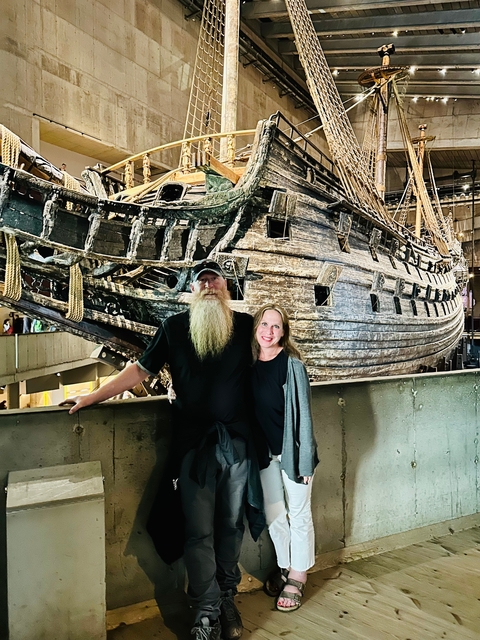 Couple in front of a large wooden ship exhibit.