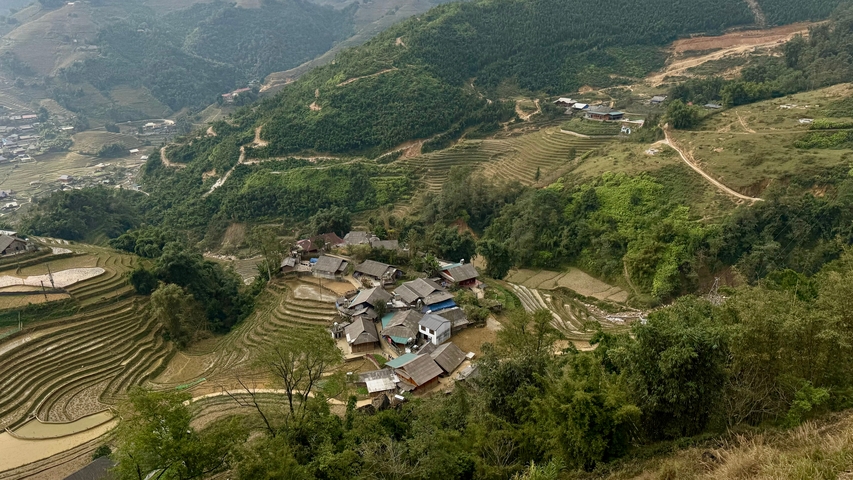 Panoramic view of rolling hills and small houses in a valley.