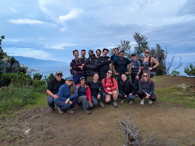 Group of hikers posing on a trail with a scenic background.