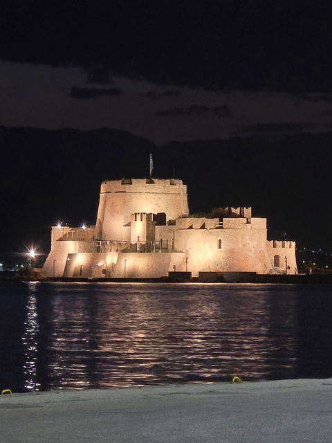 Illuminated historic castle on water at night.
