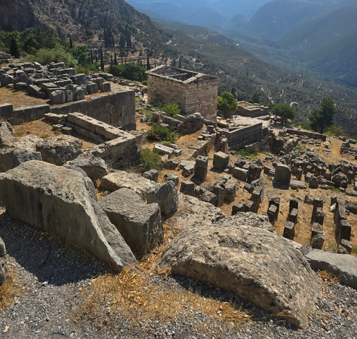 Ruins of ancient structures with a hilly landscape in the background.