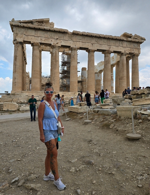 Woman posing in front of ancient columns with a group of tourists.