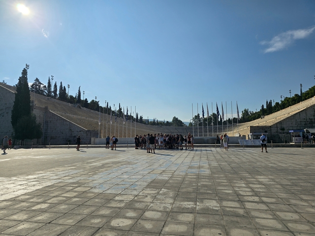 Group of tourists gathered on a square with rows of flags.