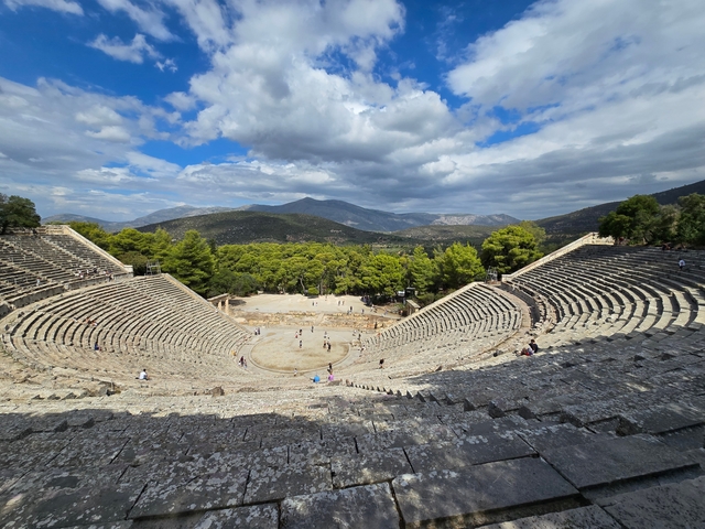 Open-air ancient theater amidst scenic mountains.