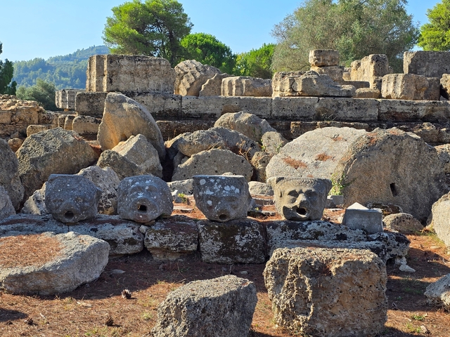 Ruins with face carvings on stones among ancient rocks.