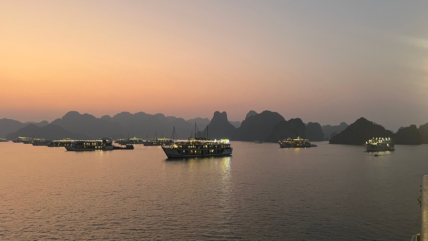 Numerous boats sailing on a serene bay at sunset.