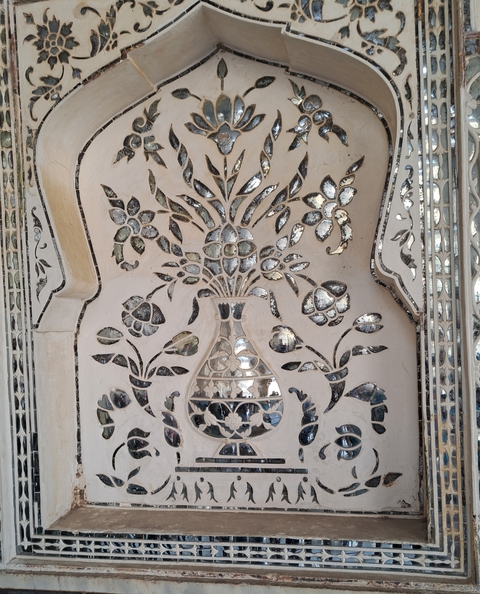 Decorative floral pattern in mirrored glass on a wall.