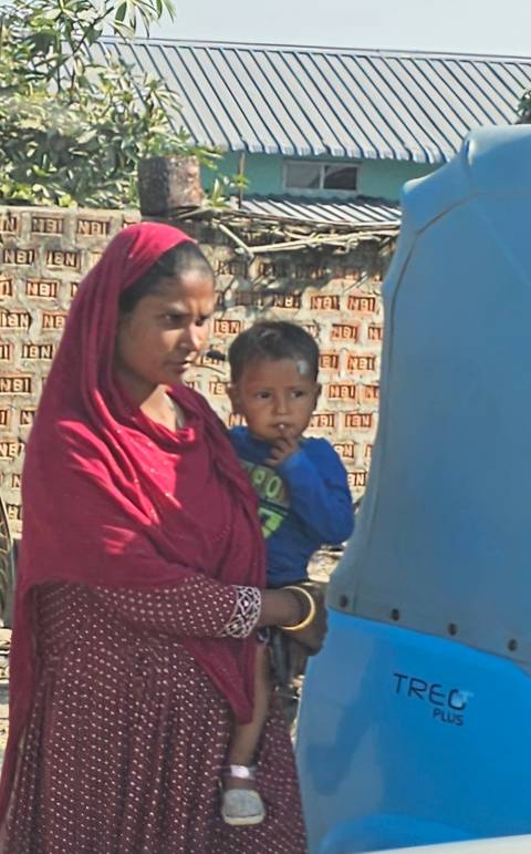 Woman holding a young child with a brick wall background.
