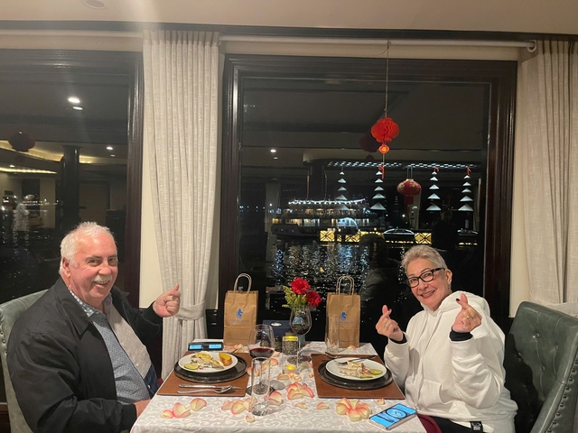 Couple dining with a view of illuminated boats at night.