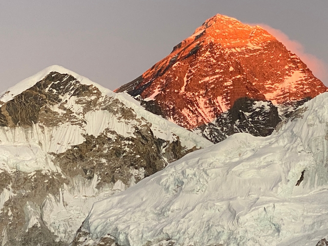The sunlit peak of Mount Everest during golden hour.