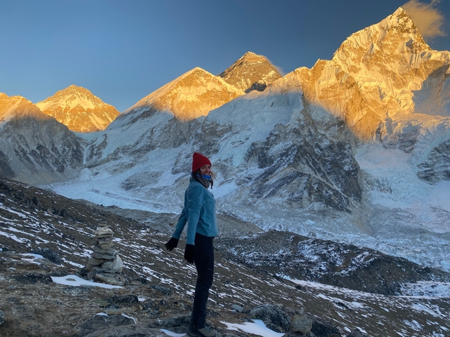 A tourist standing against the backdrop of Mount Everest.
