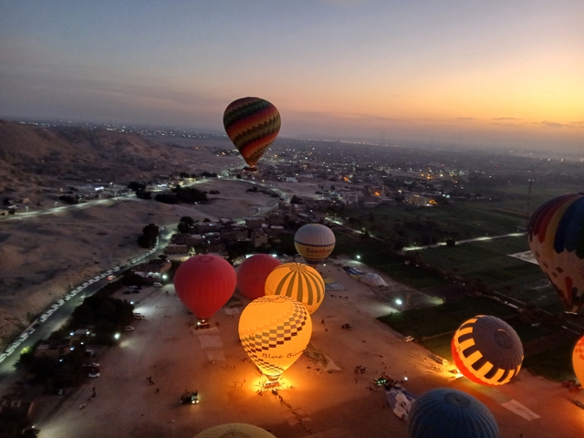 Hot air balloons floating over a desert landscape at sunrise.