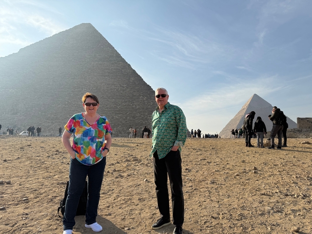 Two people posing in front of the Pyramids.