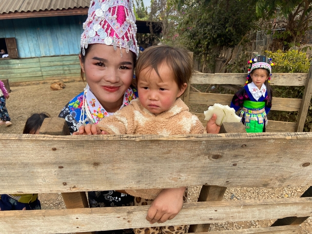 Smiling women and a child dressed in colorful traditional clothing.