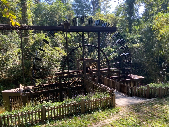 Large, outdoor wooden wheel structure in a park.