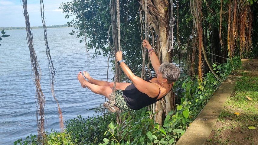 Woman swinging by a lake on a rope swing.