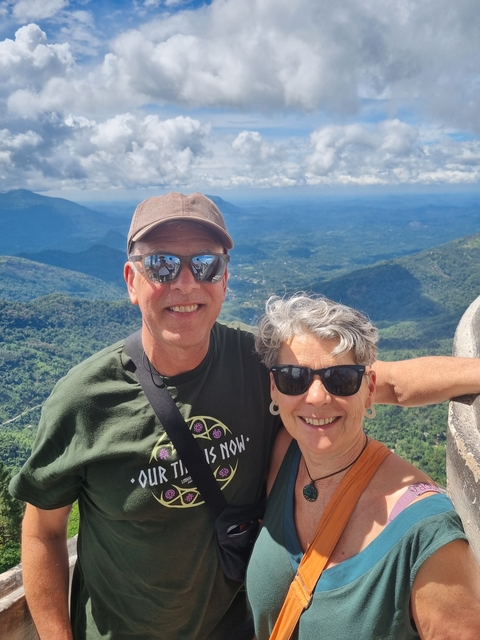 Couple posing at a viewpoint with a mountain backdrop.