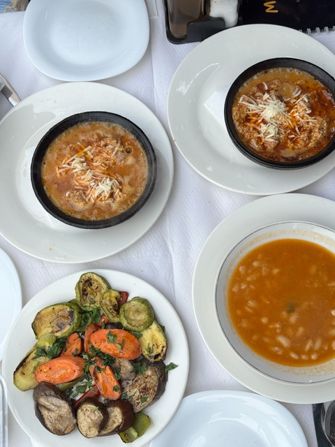 Various dishes of soup and grilled vegetables on a table.