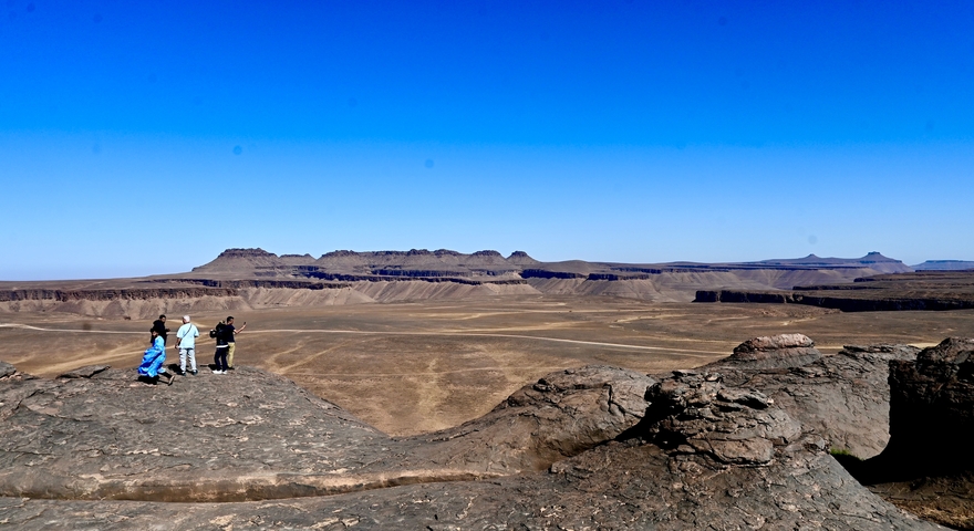 Four people on a rocky overlook with vast plains