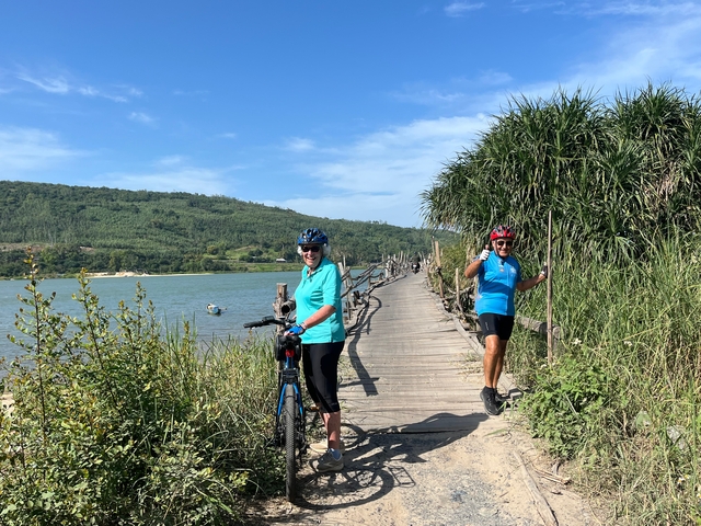 Two cyclists on a wooden bridge next to water